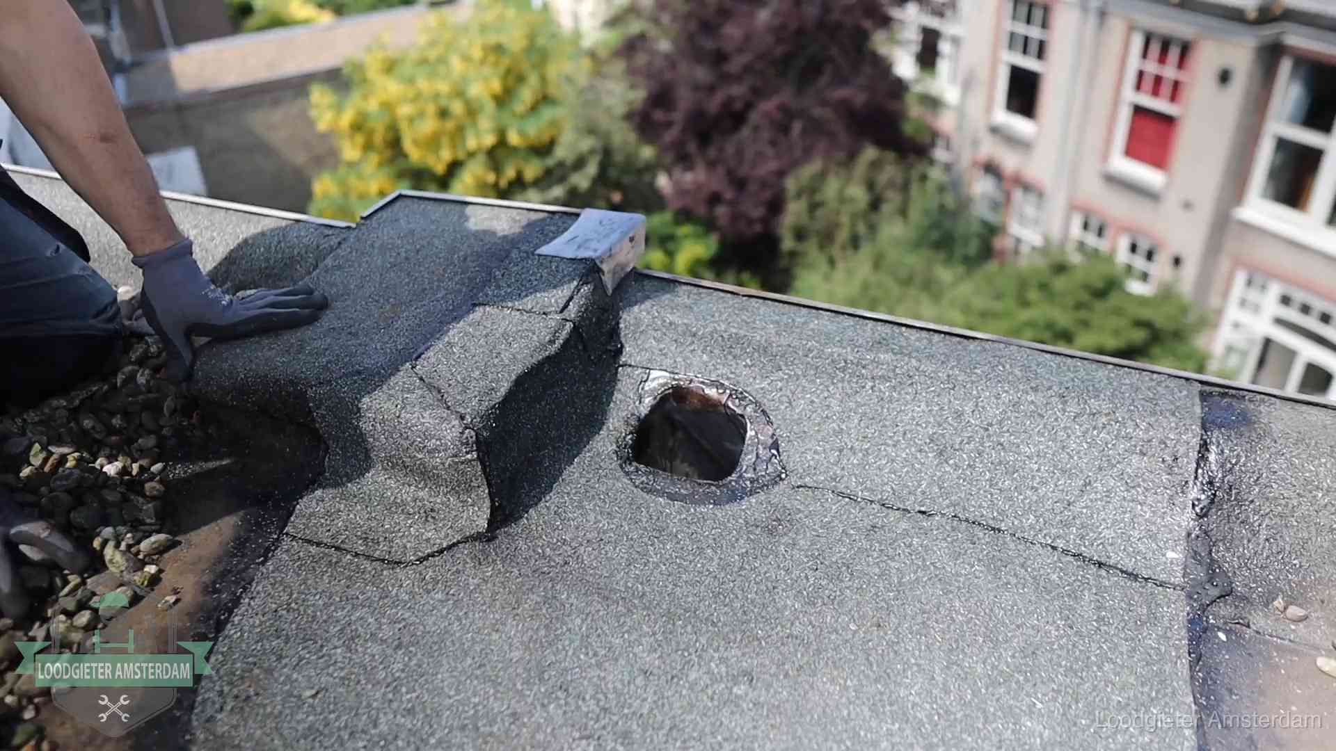 Loodgieter inspecteert een beschadigd bitumen plat dak tijdens een daklekkage-inspectie in Amsterdam