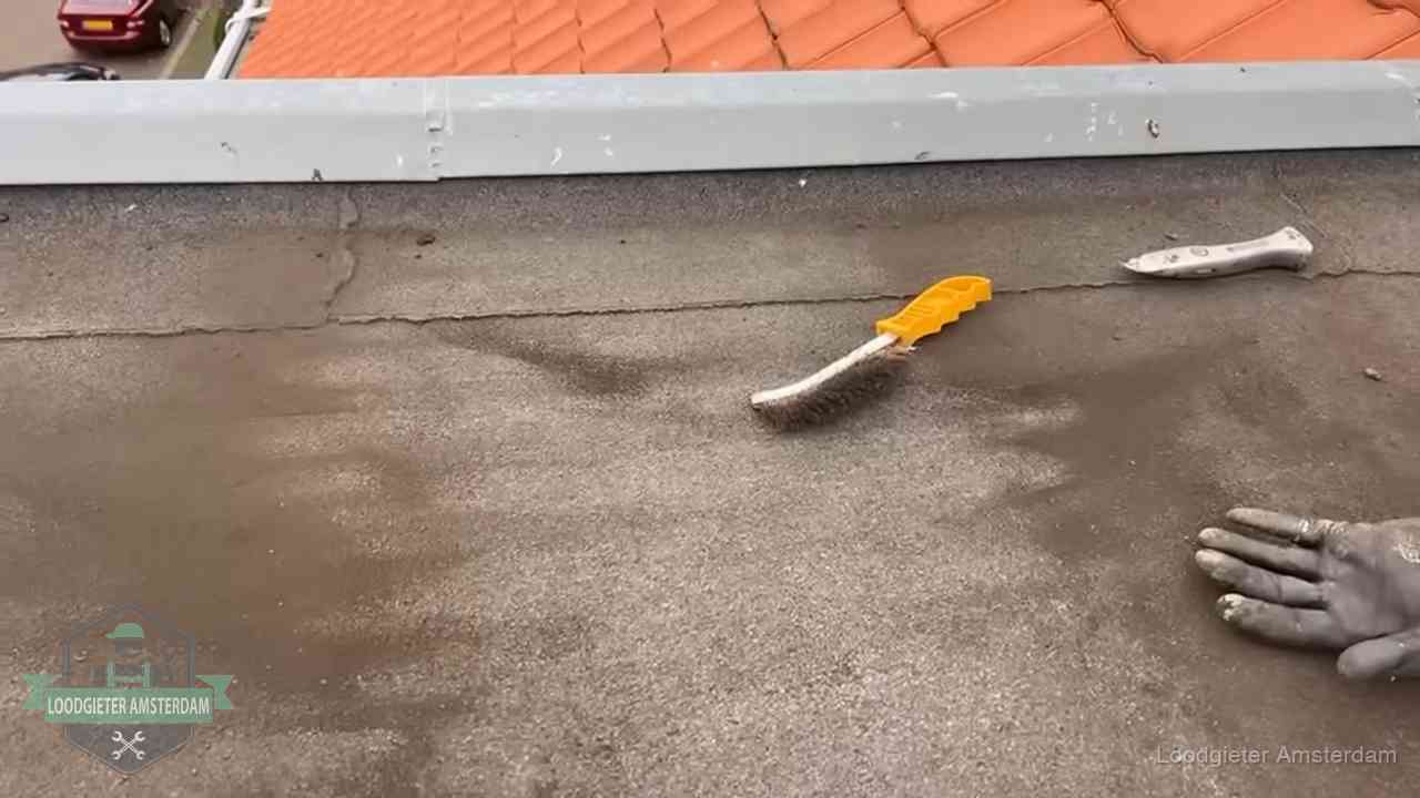 Dakdekker bereidt een bitumen plat dak voor op reparatie bij de daktrim in Amsterdam