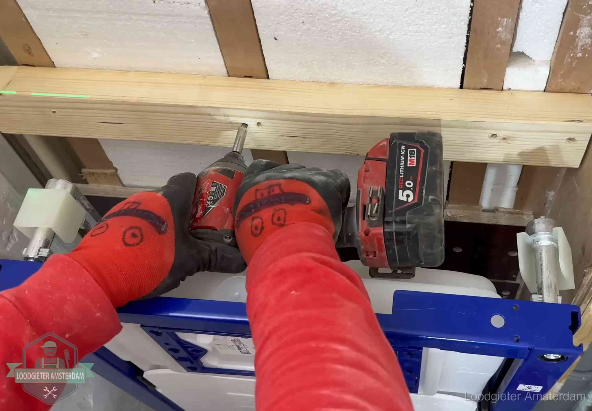Monteur bevestigt een inbouwreservoir voor een hangend toilet in Amsterdam