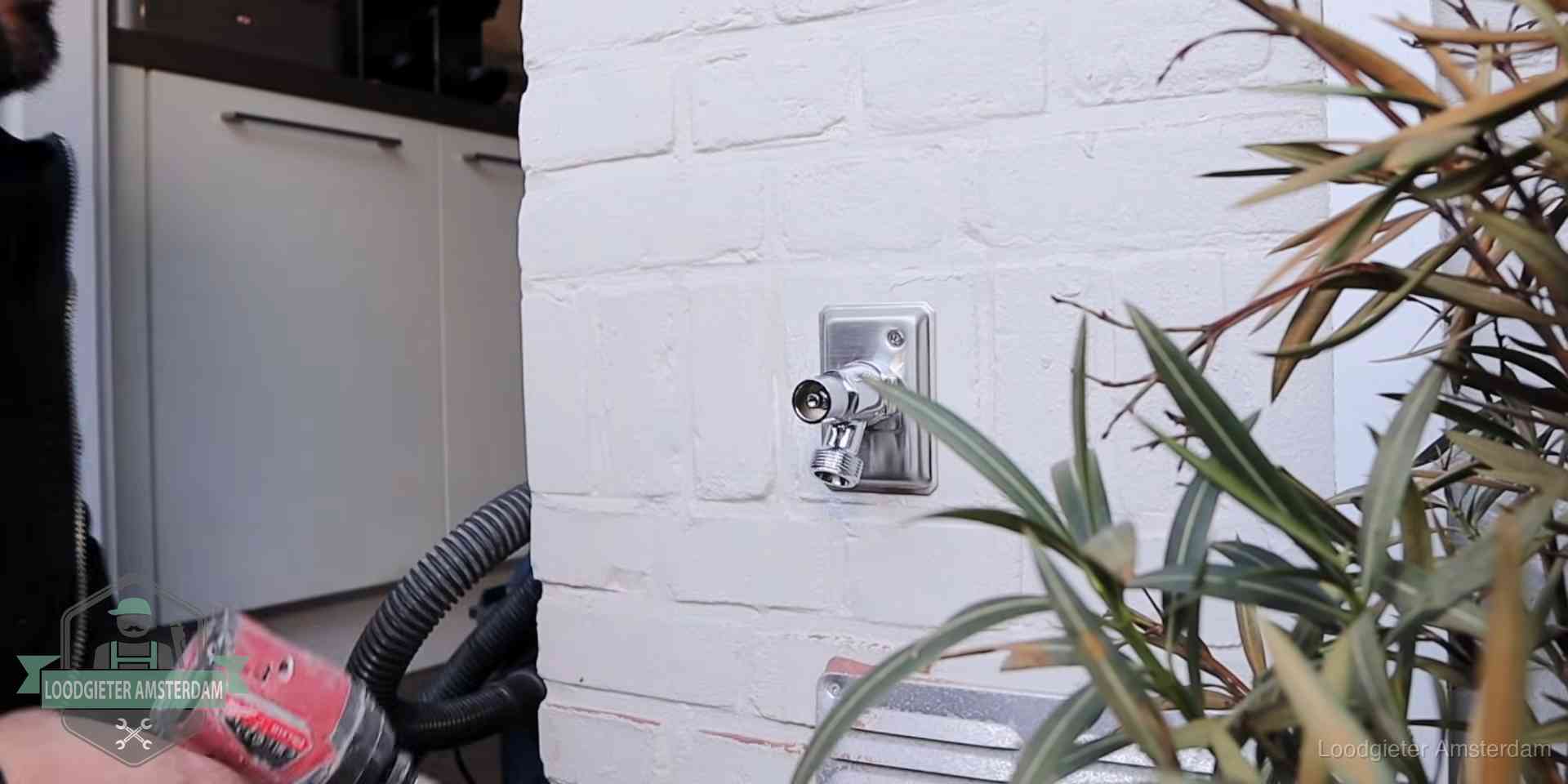Chromen kraan op een muurplaat bij een woning in Amsterdam, dichtdraaien is stap een van de lektest