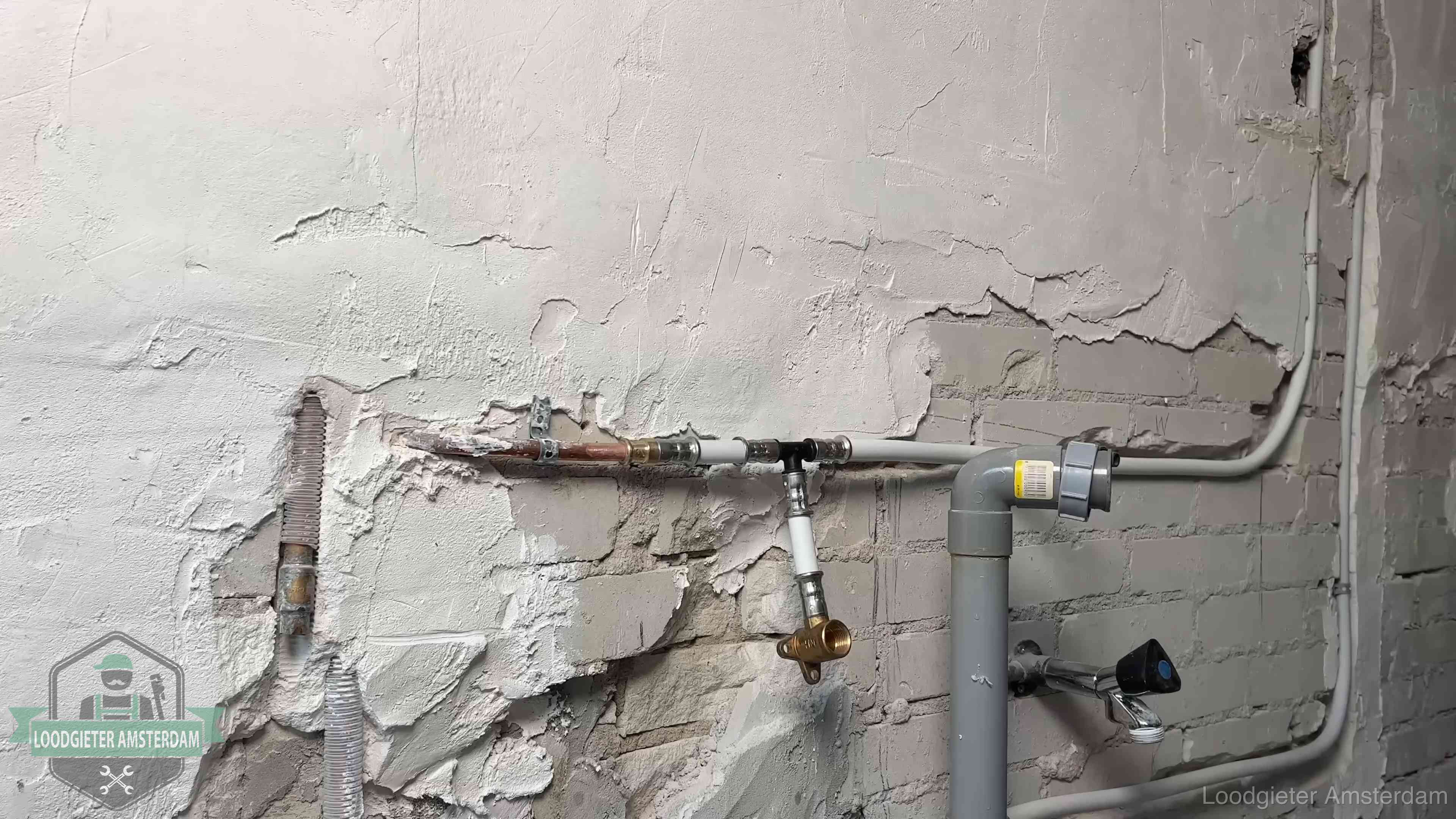 Nieuw leidingwerk naast een oud verroest leidingrestant in een woning in Amsterdam