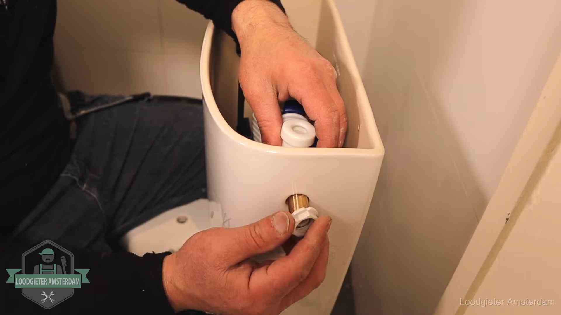 Loodgieter monteert de vlotterkraan van een stortbak bij een toilet in Amsterdam