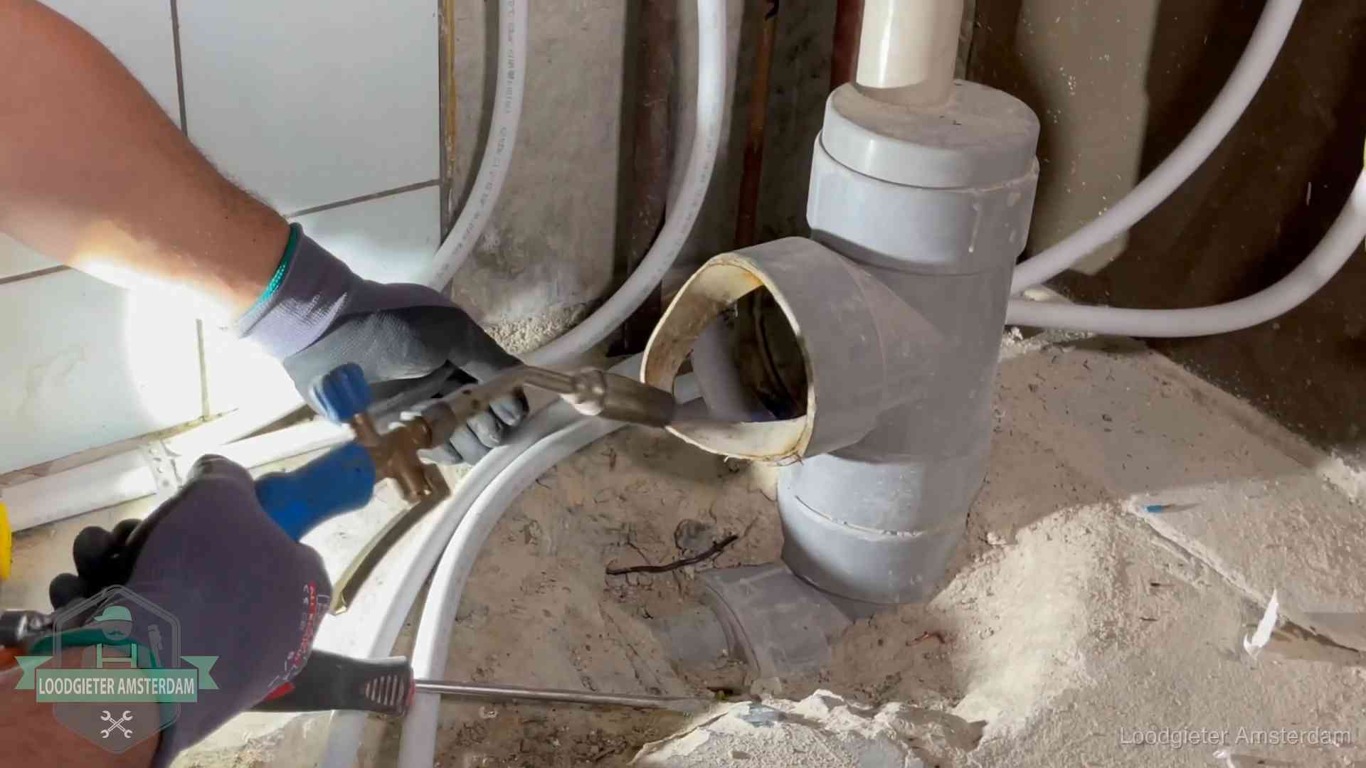 Loodgieter werkt met brander en messing kraanwerk aan leidingen in Amsterdam