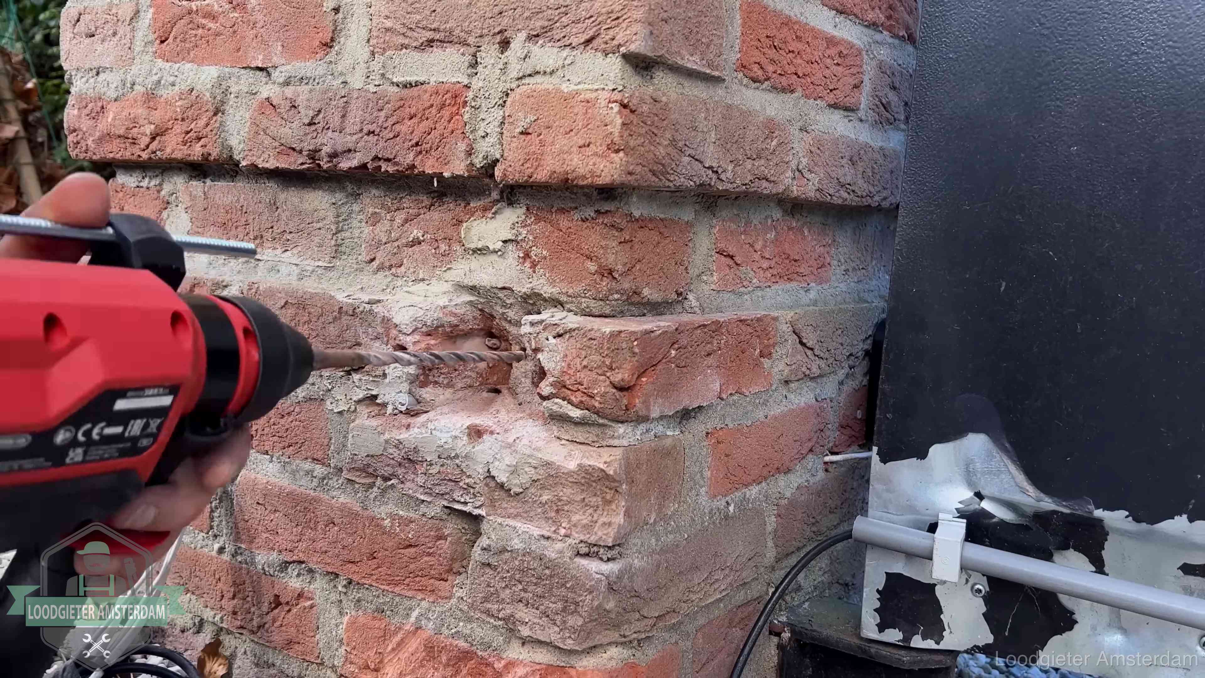Vakman boort in de buitenmuur van een woning in de regio Amsterdam
