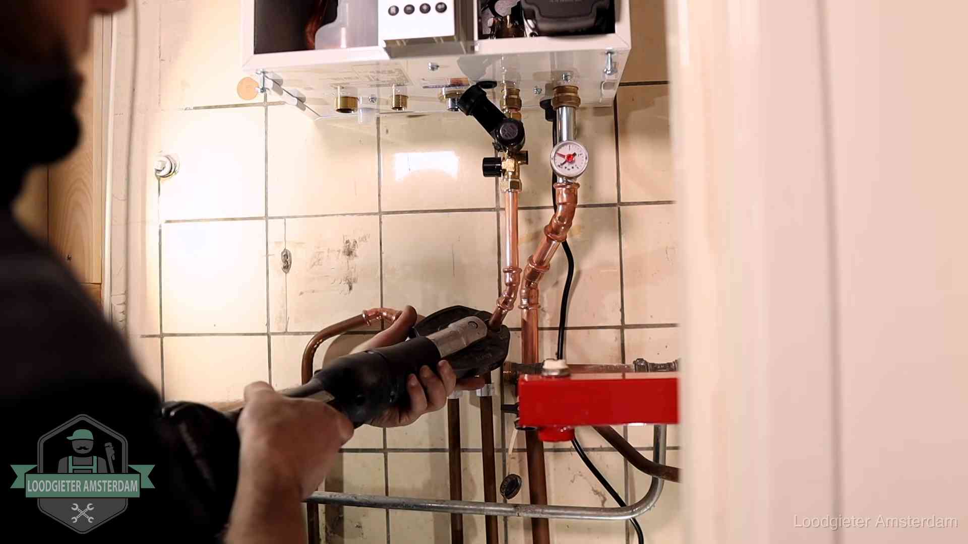 Cv-ketel onderhoud in Amsterdam Monteur werkt aan de leidingen onder een cv-ketel in Amsterdam