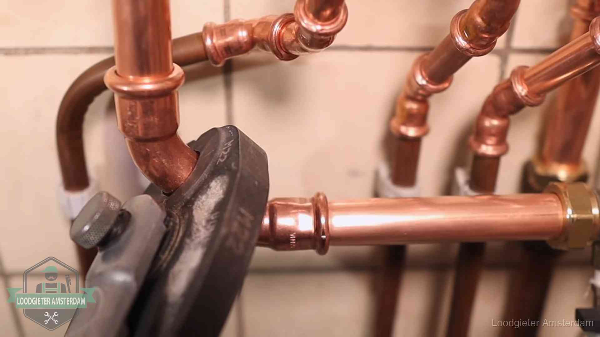 Persmachine perst een koperen fitting op nieuw leidingwerk in Amsterdam