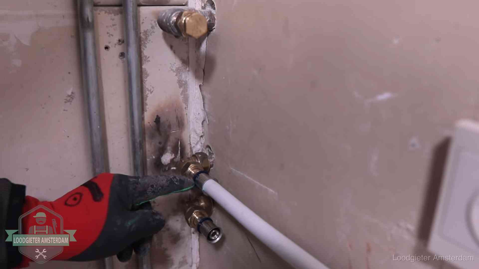 Loodgieter wijst de persfitting op nieuwe muuraansluitingen aan in een woning in Amsterdam
