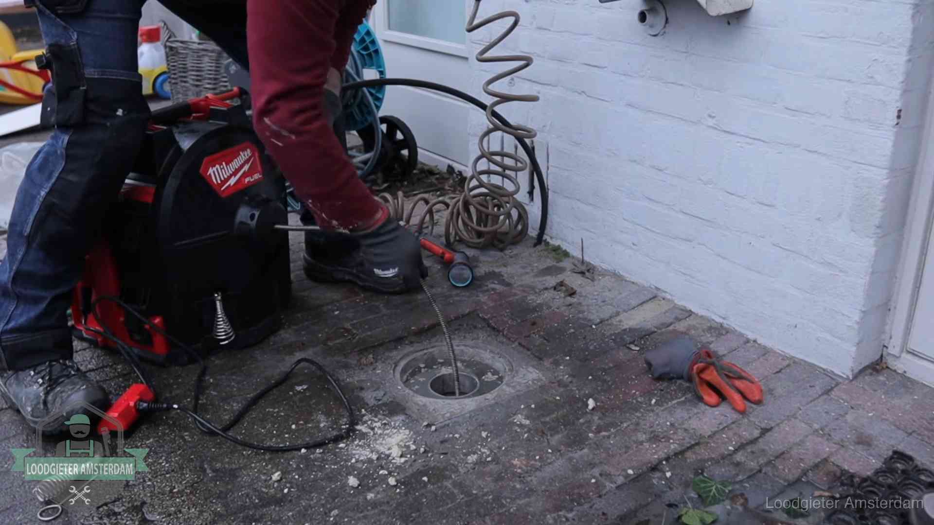 Spiraalmachine bij een ontstoppingsputje in de bestrating in Amsterdam