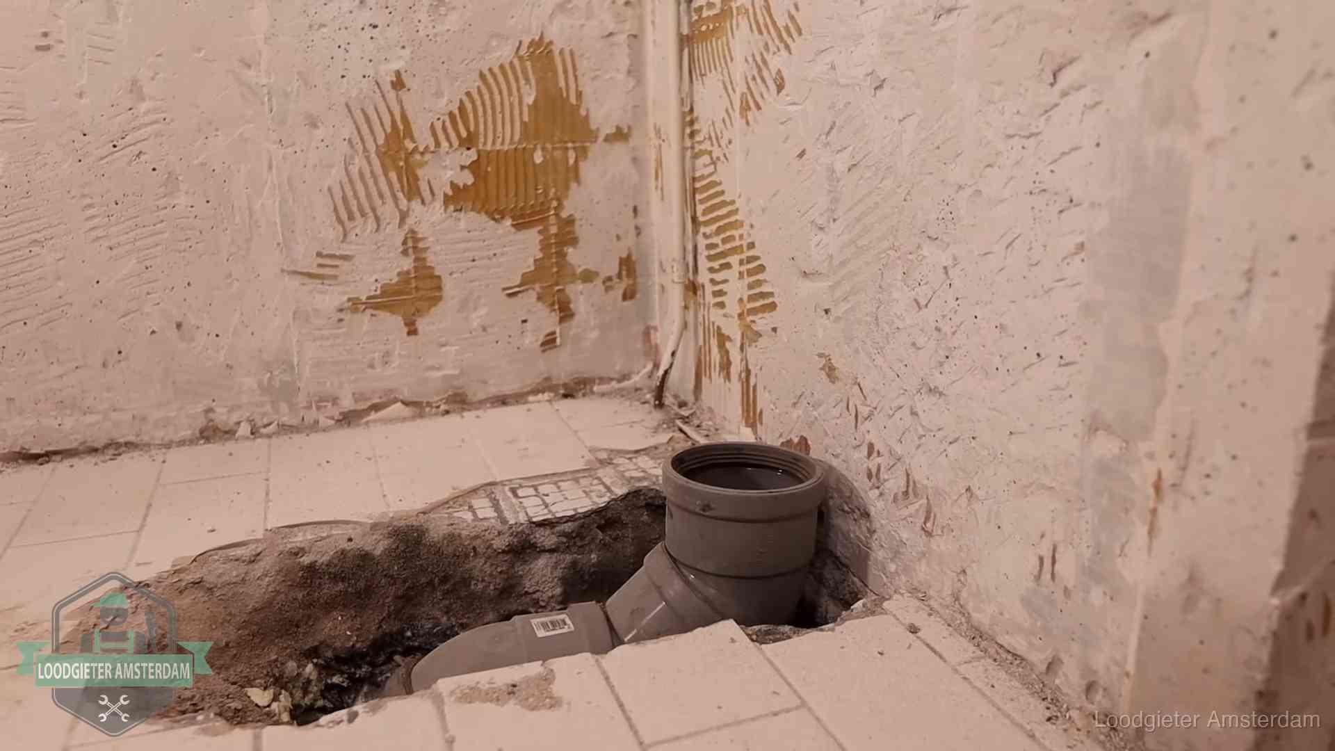 Opengebroken vloer met een nieuwe pvc-rioolbocht in een gegraven sleuf in Amsterdam