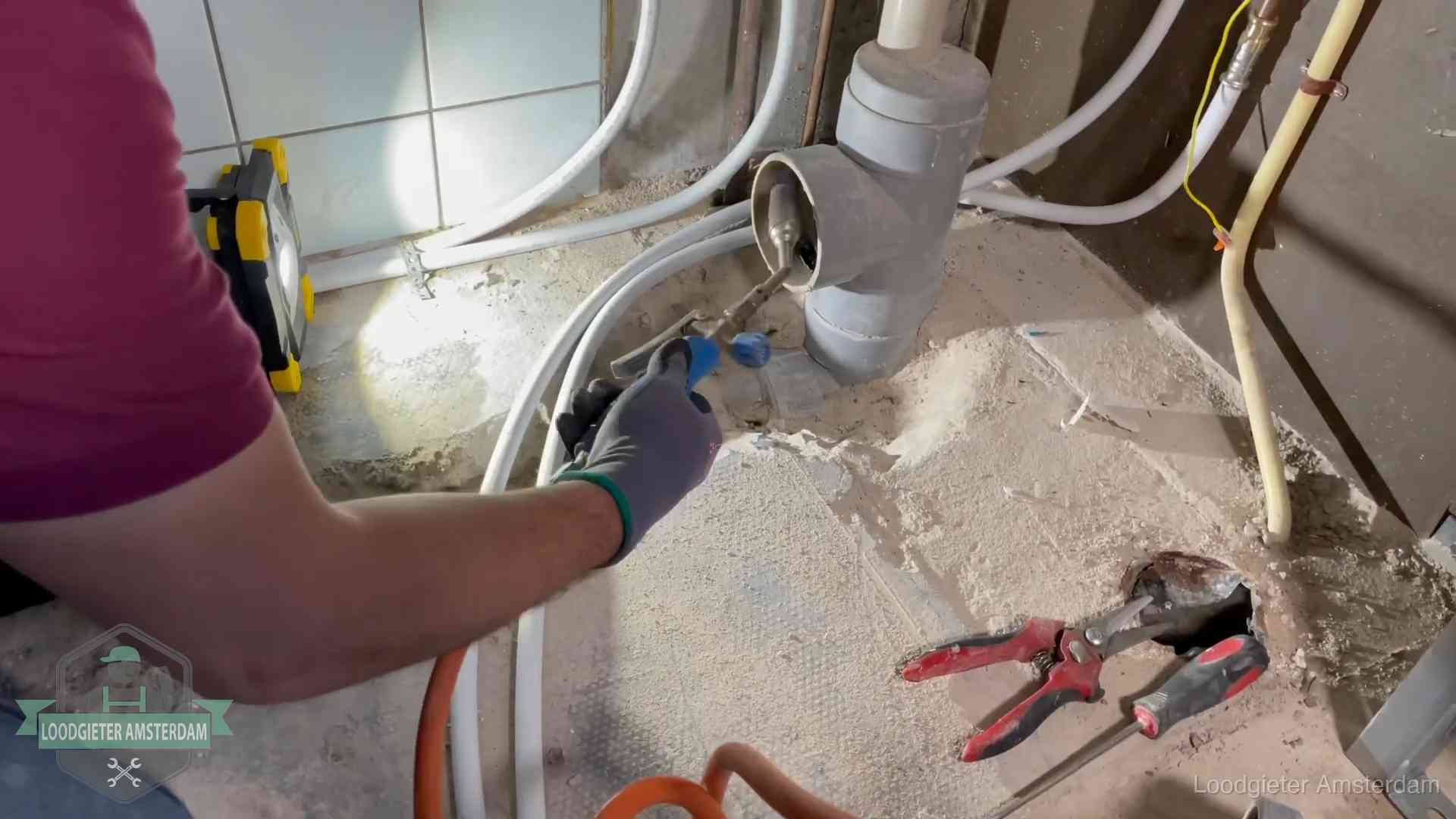 Loodgieter werkt aan leidingen bij een pvc-standleiding in een appartement in Amsterdam