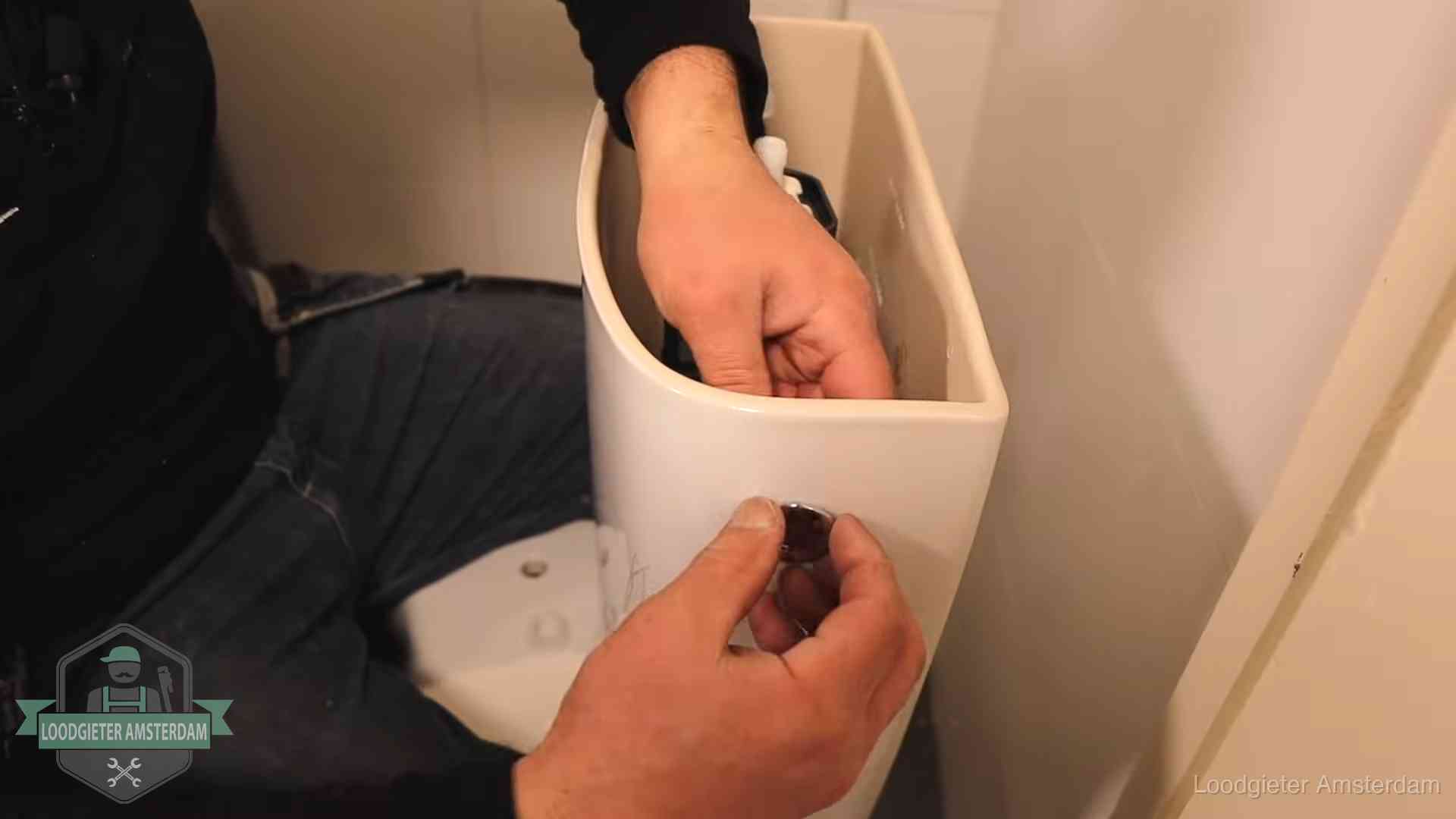 Drukknop van een duoblok-stortbak wordt gemonteerd bij een toilet in Amsterdam
