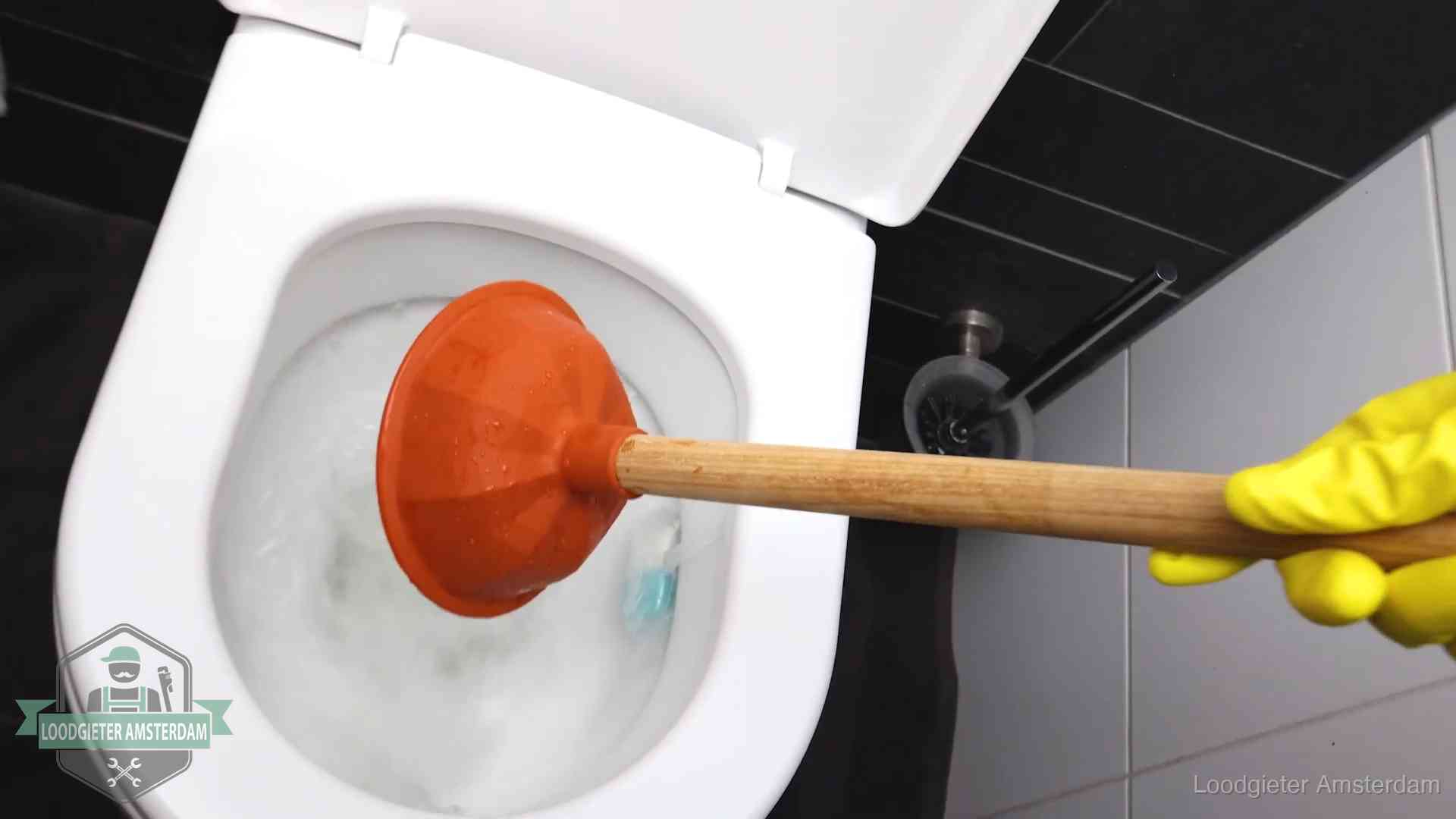 Plopper wordt in de wc-pot gedrukt bij het ontstoppen van een toilet in Amsterdam