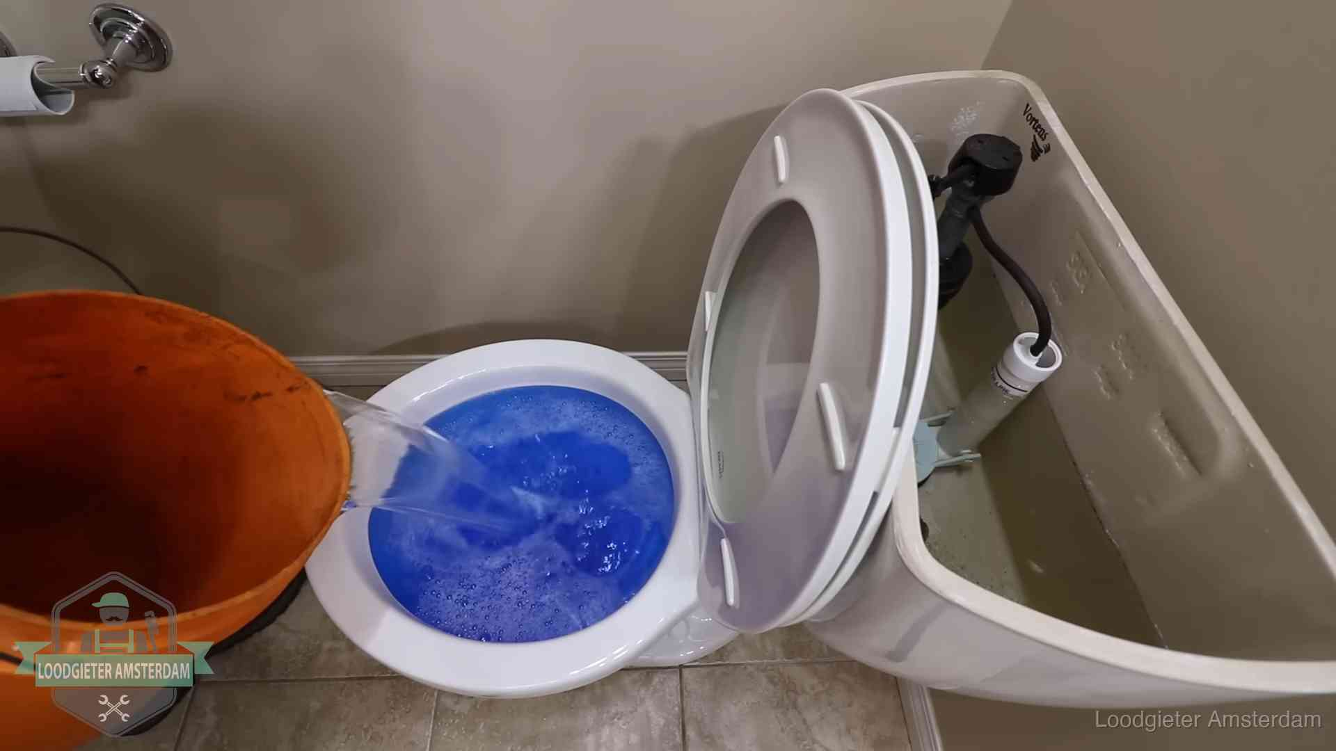 Water bij de wc-pot wordt met een emmer weggewerkt om schade te beperken in Amsterdam
